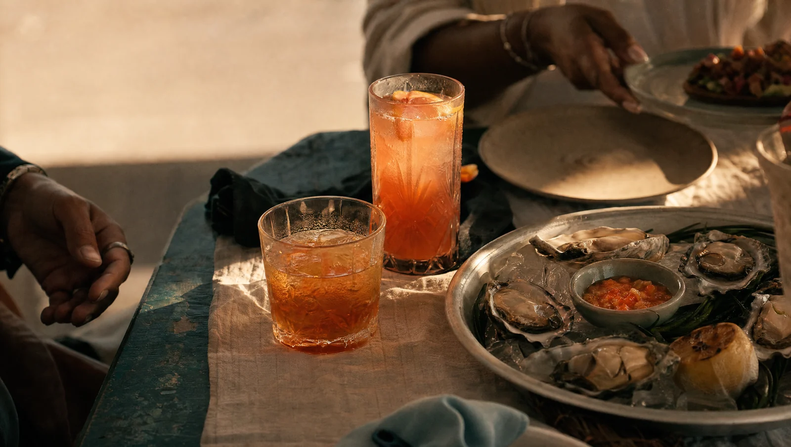 Amber drinks and a shared meal on a warm wood table